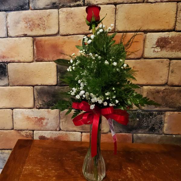 A single, elegant rose bud displayed in a minimalist ceramic vase.